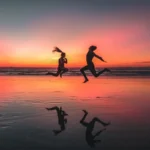 Un homme et une femme courent sur une plage marocaine au coucher du soleil