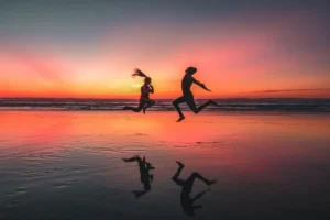 Un homme et une femme courent sur une plage marocaine au coucher du soleil