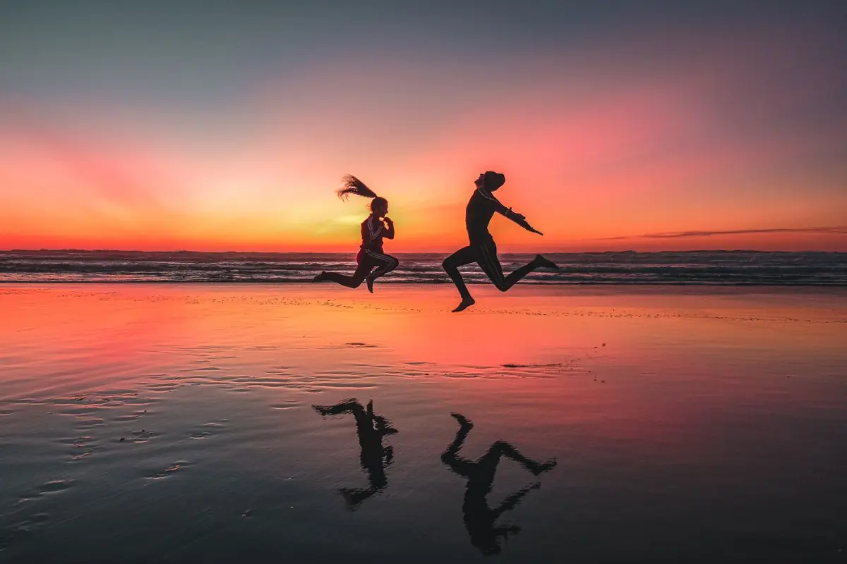 Un homme et une femme courent sur une plage marocaine au coucher du soleil