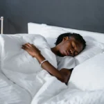 Femme endormie sous une couette blanche dans une chambre calme, article sur le sommeil et la récupération du coureur au Maroc