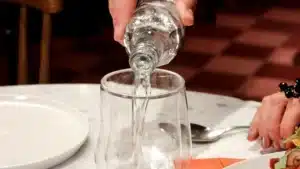 Une table dressee avec des assiettes servies et une main qui verse de l eau dans un verre