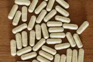 كبسولات بيضاء مبعثرة على طاولة خشبية من الأعلى، مقال المكملات التي لا يجب الجمع بينها