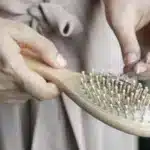 صورة توضيحية: يد كتحيد الشعر من مشطة خشبية