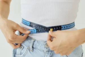 قياس محيط الخصر بشريط قياس أزرق فوق قميص أبيض، مقال هل الجري ينقص الوزن