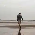 رجل يمشي على شاطئ رطب نحو البحر مصوَّراً من الخلف، مقال الجري بعد الأربعين في المغرب