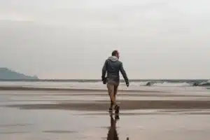 رجل يمشي على شاطئ رطب نحو البحر مصوَّراً من الخلف، مقال الجري بعد الأربعين في المغرب