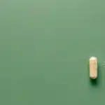 صورة توضيحية: كبسولة وحدة ومسحوق فاتح فوق خلفية خضراء