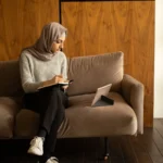 مرا جالسة فالصالون كتكتب ملاحظات فكناش، صورة توضيحية