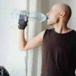 Un homme boit a une bouteille d eau apres l entrainement, lumiere naturelle