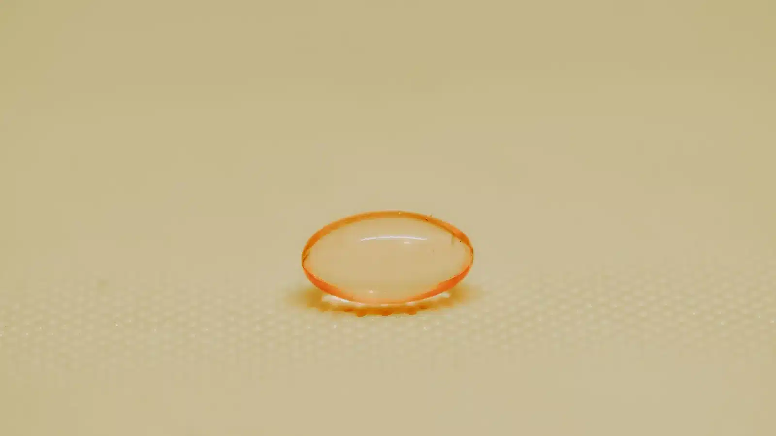 Photographie d’illustration : une capsule molle orangée posée sur une surface beige