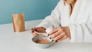 Une femme melange une poudre dans un verre d eau dans une cuisine, lumiere du matin