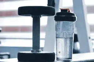 Haltère et shaker posés sur un banc de salle de musculation, guide des compléments pour débutant au Maroc