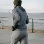 Coureur d'âge mûr vu de dos, bonnet et veste grise, sur un quai au bord de l'eau, article sur le running après 40 ans au Maroc