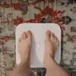 Pieds nus sur une balance posée sur un tapis à motifs, article sur le running et la perte de poids au Maroc