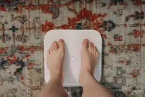 Pieds nus sur une balance posée sur un tapis à motifs, article sur le running et la perte de poids au Maroc
