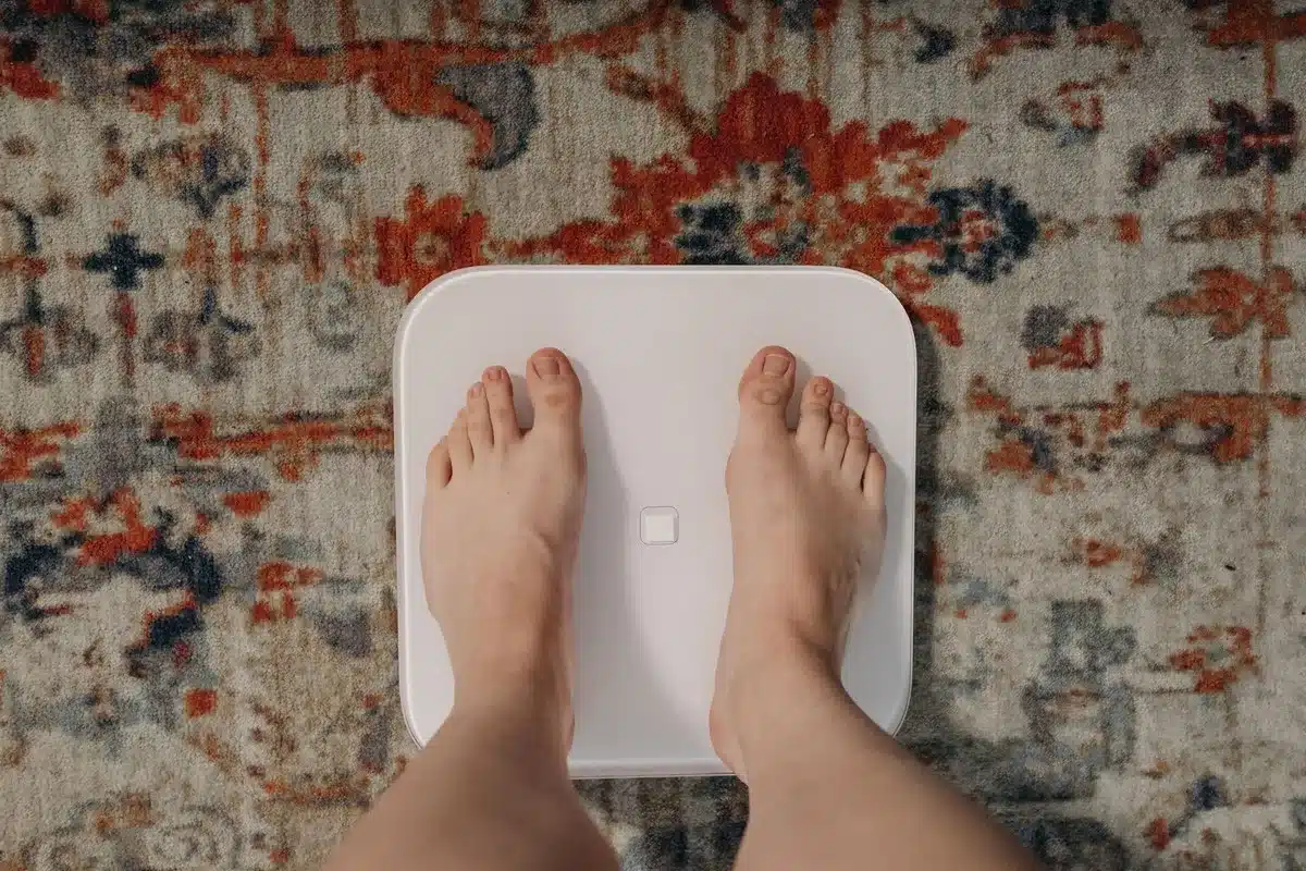 Pieds nus sur une balance posée sur un tapis à motifs, article sur le running et la perte de poids au Maroc