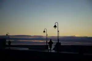 Silhouette d'un coureur sur une corniche au coucher du soleil, guide pour commencer le running au Maroc sans se blesser