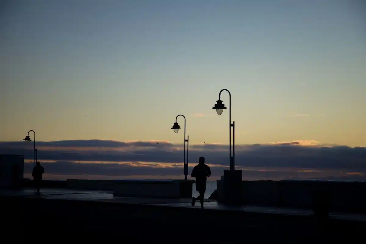 Silhouette d'un coureur sur une corniche au coucher du soleil, guide pour commencer le running au Maroc sans se blesser