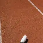 Gourde blanche posée sur une piste d'athlétisme ocre au soleil, guide de l'hydratation du coureur sous la chaleur au Maroc