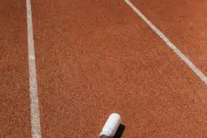Gourde blanche posée sur une piste d'athlétisme ocre au soleil, guide de l'hydratation du coureur sous la chaleur au Maroc