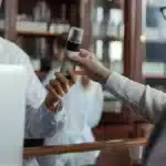 Un pharmacien en blouse conseille une cliente devant un rayon de complements