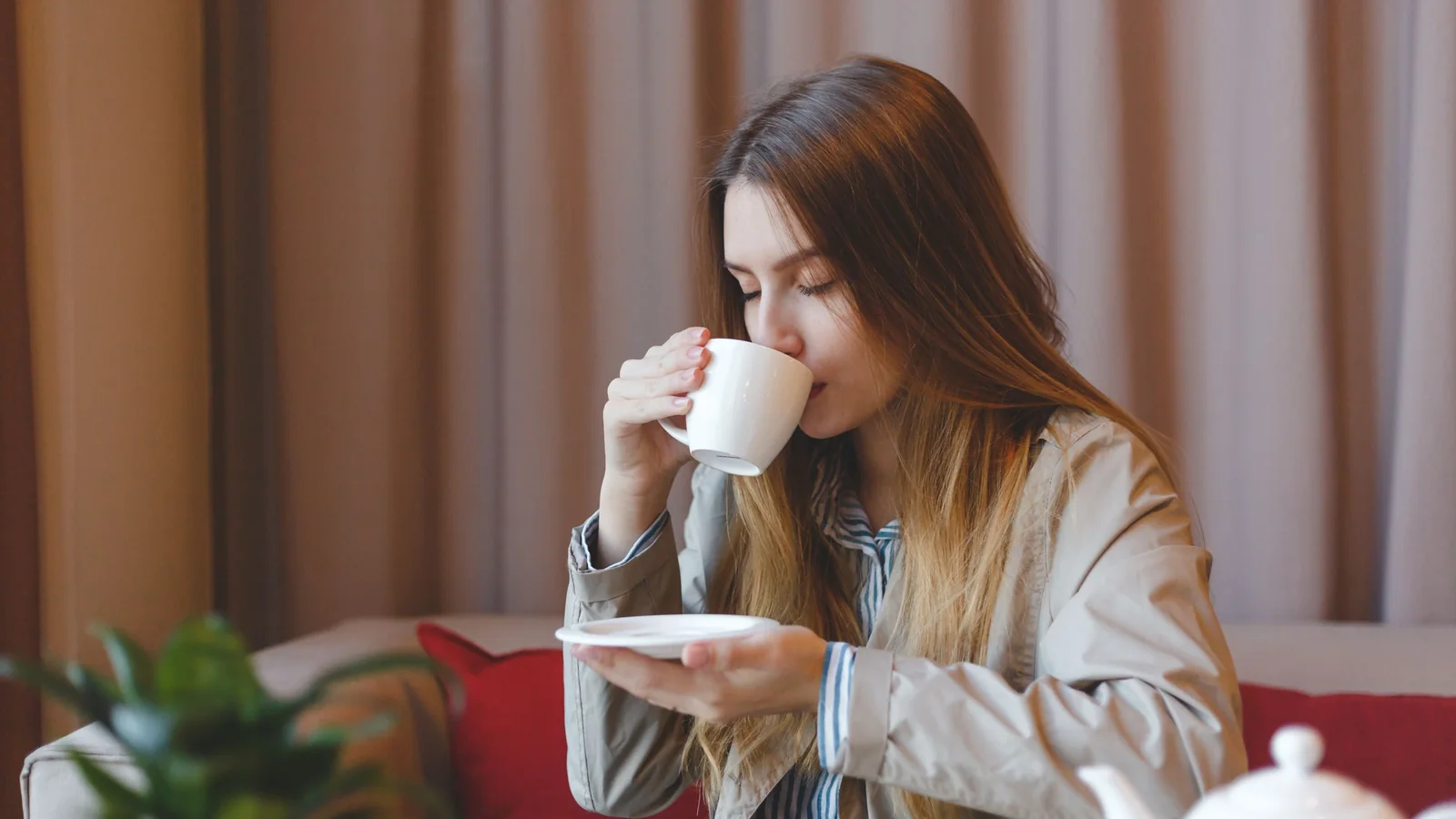 Femme buvant un thé à une table dans une pièce calme, photographie d'illustration