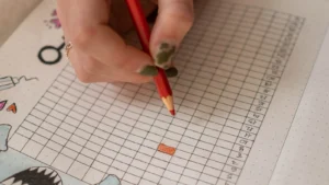 Main notant le suivi des symptômes sur une grille de carnet, photographie d'illustration