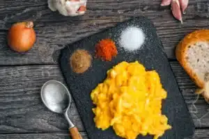 Œufs brouillés sur une planche noire avec épices, oignon et pain, article sur la récupération après la course au Maroc