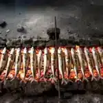 سردين طازج يُشوى على الفحم، دخان خفيف، سوق شعبي