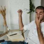 Homme faisant une pause à son bureau, lunettes à la main, photographie d'illustration