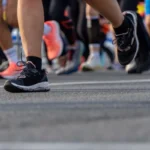 Gros plan sur les pieds et les jambes de coureurs en mouvement sur l'asphalte d'une course sur route, article sur la nutrition du marathon de Marrakech