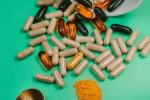 Gélules, capsules souples et poudre de compléments alimentaires avec une cuillère sur fond vert, guide des prix des compléments au Maroc
