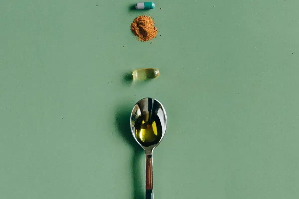 Une gélule, une poudre, une capsule d'huile et une cuillère alignées sur un fond vert, guide honnête des suppléments pour coureurs au Maroc