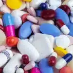 Un grand melange de comprimes et de gelules de toutes couleurs, illustrant le cumul de plusieurs complements