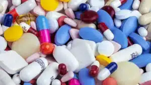 Un grand melange de comprimes et de gelules de toutes couleurs, illustrant le cumul de plusieurs complements