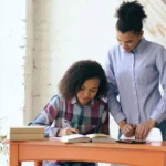 Parent aidant une adolescente à une table près d'une fenêtre, photographie d'illustration