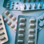 Plusieurs plaquettes de comprimes posees sur une surface bleue, evoquant les formats delivres en pharmacie