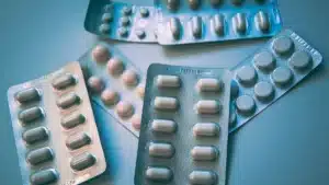 Plusieurs plaquettes de comprimes posees sur une surface bleue, evoquant les formats delivres en pharmacie
