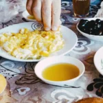 Photographie d’illustration : table de petit-déjeuner marocain avec pain, œufs brouillés, olives et thé