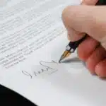 Main qui signe une lettre au stylo plume