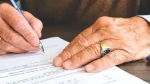 يدان توقّعان على ورقة فوق مكتب خشبي
